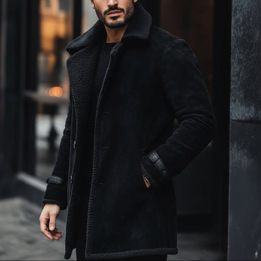 Man wearing a black coat standing against a dark background