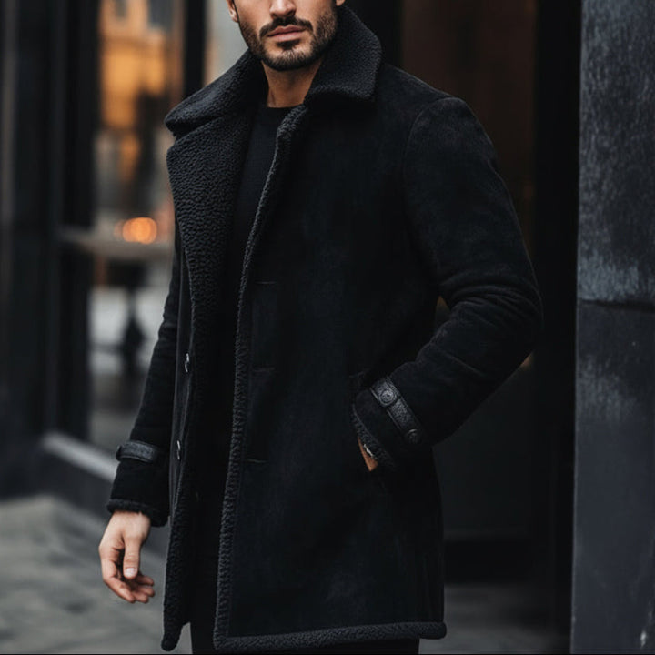 Man wearing a black coat standing against a dark background
