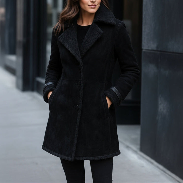 Woman wearing a black coat standing on a city street.