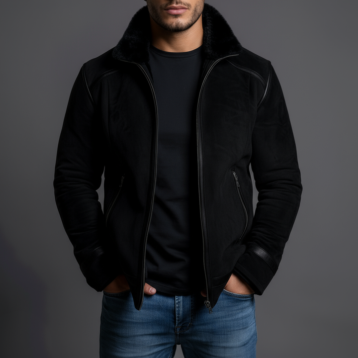 Man wearing a black jacket and blue jeans against a gray background