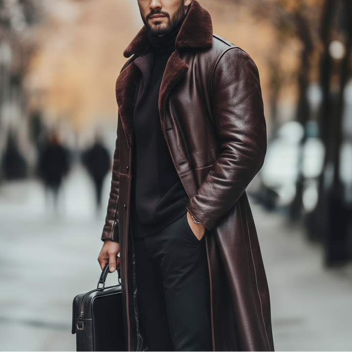 Man in a long brown coat holding a suitcase on a blurred street background