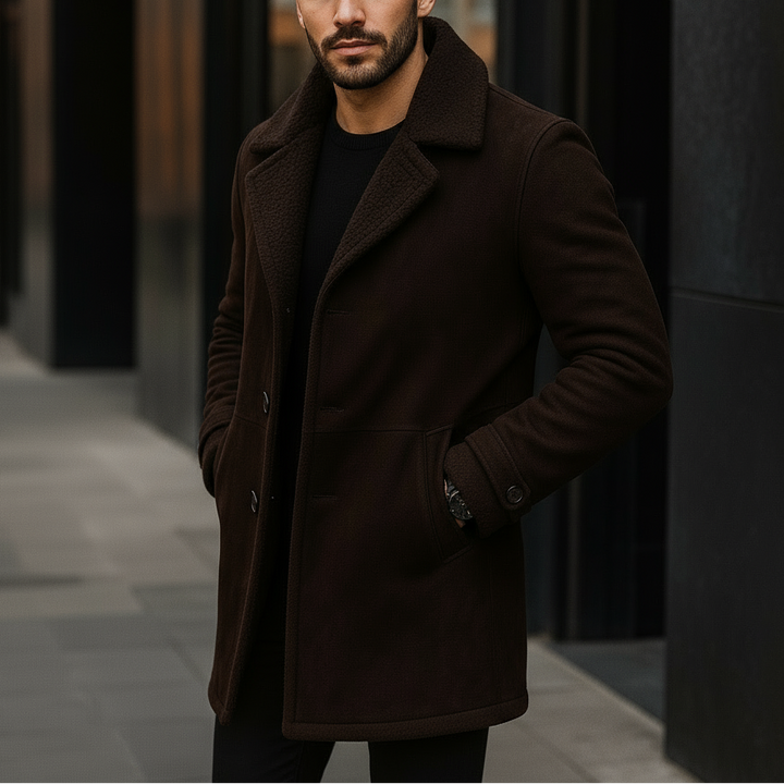 Man wearing a dark brown coat standing on a city street.